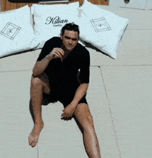 a man laying on the ground with pillows that say kilian on them