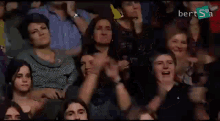 a group of people are sitting in a stadium applauding and clapping .