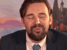 a man with a beard wearing a suit and tie is making a funny face