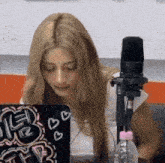 a woman is sitting in front of a microphone and a laptop with hearts on it