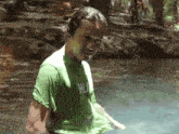 a man in a green shirt that says hulk is standing in a body of water