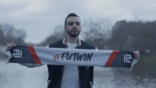 a man holding a scarf that says futwin