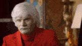 a man wearing a red suit and white wig is making a funny face .