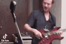 a man is playing a guitar in a room next to a cello .