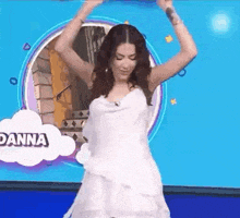 a woman in a white dress is dancing on a stage with her arms in the air .
