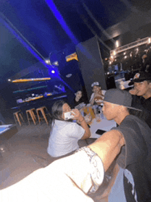 a man wearing a watch takes a picture of a group of people in a bar