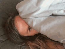 a woman is laying in bed with a blanket over her face .