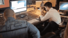 a man sitting at a desk with a shirt that says ' n.i.e. ' on it