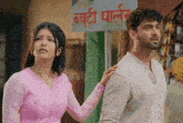 a man and a woman are standing in front of a sign that says ' ब्यूटी पार्लर ' on it