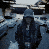 a woman wearing headphones and a hat that says ' porsche ' on it is walking down a street