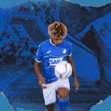 a man in a blue shirt with the word sap on it is throwing a soccer ball
