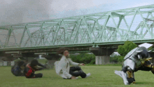 a group of people are laying on the grass under a bridge