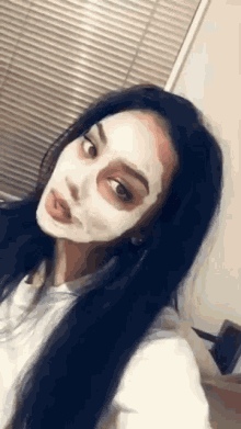 a woman is wearing a white mask on her face and sticking her tongue out .