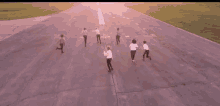 a group of people are running down an empty runway .