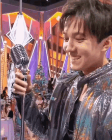 a young man is holding a microphone in front of a crowd .