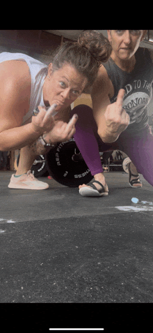 a woman wearing a shirt that says " road to the ironman " giving the middle finger