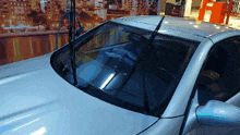 a silver car is parked in front of a picture of a city at night