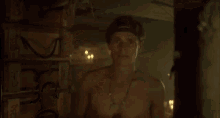 a man is smoking a cigarette in a dark room with a hat on .