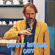 a man in a yellow jacket is pouring a drink into a glass with a caption saying " cayyyy istiyorum cayyy "