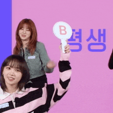 a girl in a pink and black striped shirt is holding a sign that says b on it