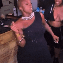a woman in a black dress is dancing with another woman in a bikini at a party .