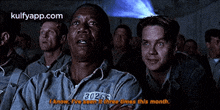 a group of men are watching a movie and one of them has a tag that says 3026