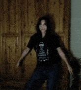 a woman wearing a jack daniels t-shirt is dancing in front of a wooden wardrobe