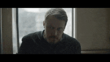 a man with a beard is looking out a window .