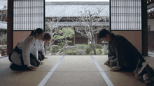 a group of people are kneeling on a mat in a room