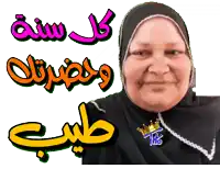 a woman wearing a hijab and a necklace with a crown on it stands in front of arabic writing