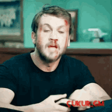 a man with blood coming out of his nose is wearing a black shirt and has the word gm on the bottom right