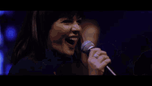 a woman is singing into a microphone on a stage