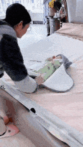 a woman is putting a baby in a blanket on a bed .