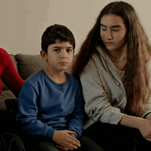 a boy in a blue shirt sits next to a girl in a grey sweatshirt
