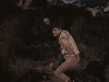 a man is running through a forest with his arms outstretched in a movie .