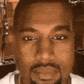 a close up of kanye west 's face with a beard and a white shirt .