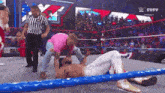 a man is laying on the ground in a wrestling ring with a referee .