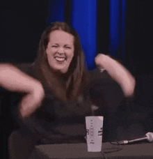 a woman is sitting at a table with a microphone and a cup that says " i love you "