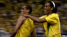 two soccer players are hugging each other on a soccer field .