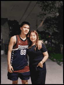 a man wearing a basketball jersey with the number 88 on it stands next to a woman
