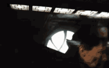 a person is standing in a dark room with a basketball shaped window .