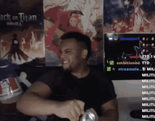 a man is smiling while holding a can of soda in front of a wall with posters of attack on titan .