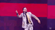 a man in a suit and tie is dancing on a stage in front of a red background .