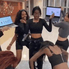 a group of women are dancing in front of a laptop that says ' i 'm ' on it
