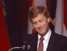 a man in a suit and tie is smiling with a yellow star on his forehead
