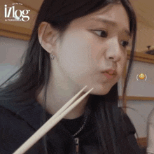 a girl is eating with chopsticks and the word vlog is on the bottom