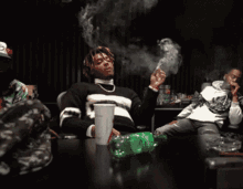 a man smoking a cigarette while sitting at a table with a sprite bottle on it