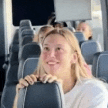a woman is smiling while sitting on a bus .