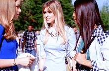 three women are standing next to each other talking to each other .