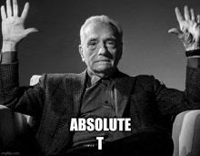 a man in a suit is sitting in a chair with his hands in the air and the words absolute t on the bottom right